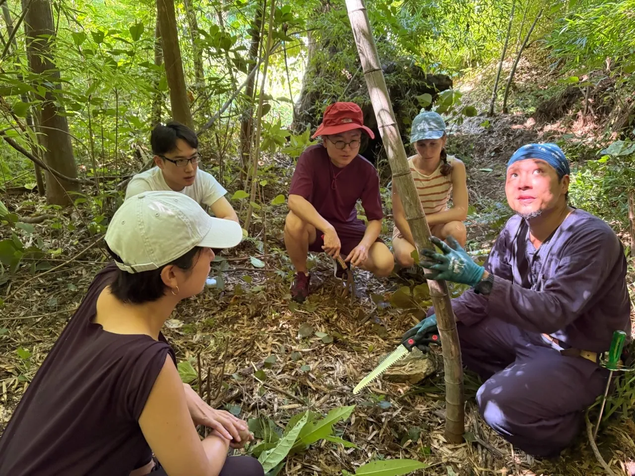Masanori Seto, PhD (right), ecologist and civil engineer, explains how to cut bamboo stems 
part of a larger project to restore regional woodlands.
